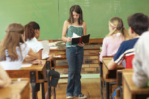 Female student standing in front of class reading her book